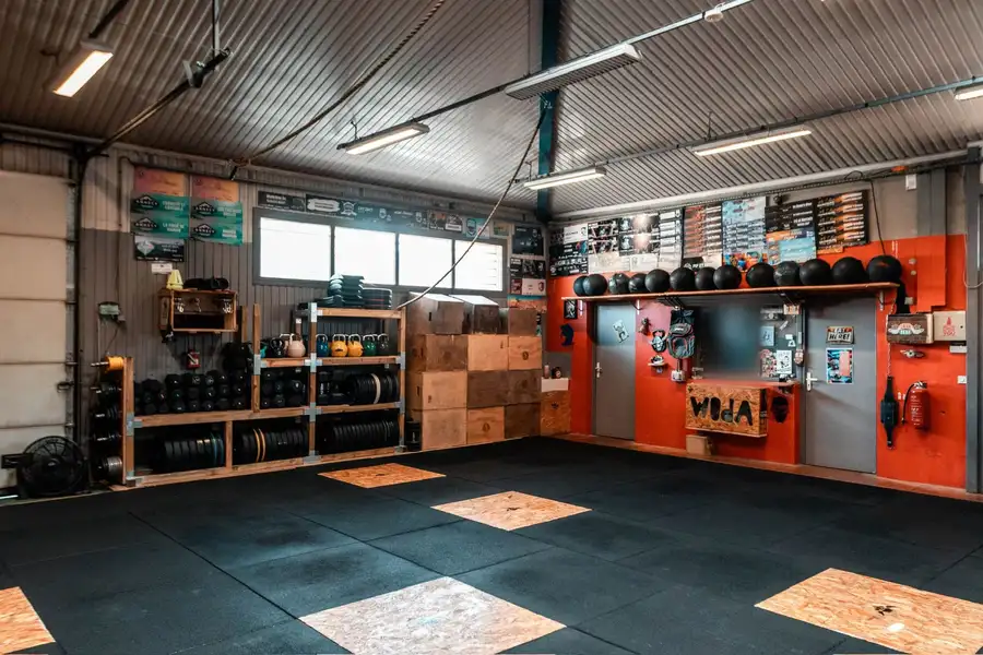 L'entrée de la box : mur rouge, porte grise et panneau Woda gravé dans l'OSB.