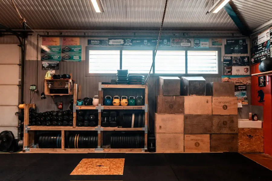 Kettlebells, box de saut et médecine-balls sur les étagères en bois.