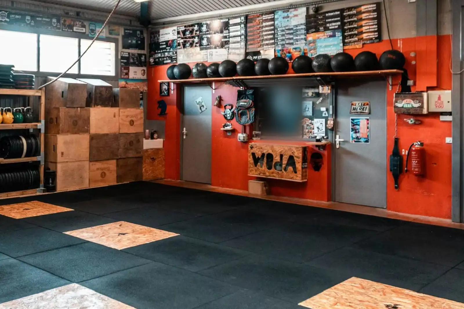 L'entrée de la box CrossFit Woda à Gap&nbsp;: le mur rouge, les portes et le panneau Woda.