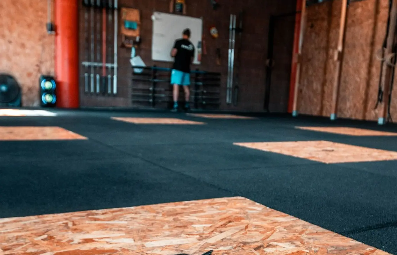 Carré d'OSB encastré dans le sol caoutchouc de la box, vu de près.